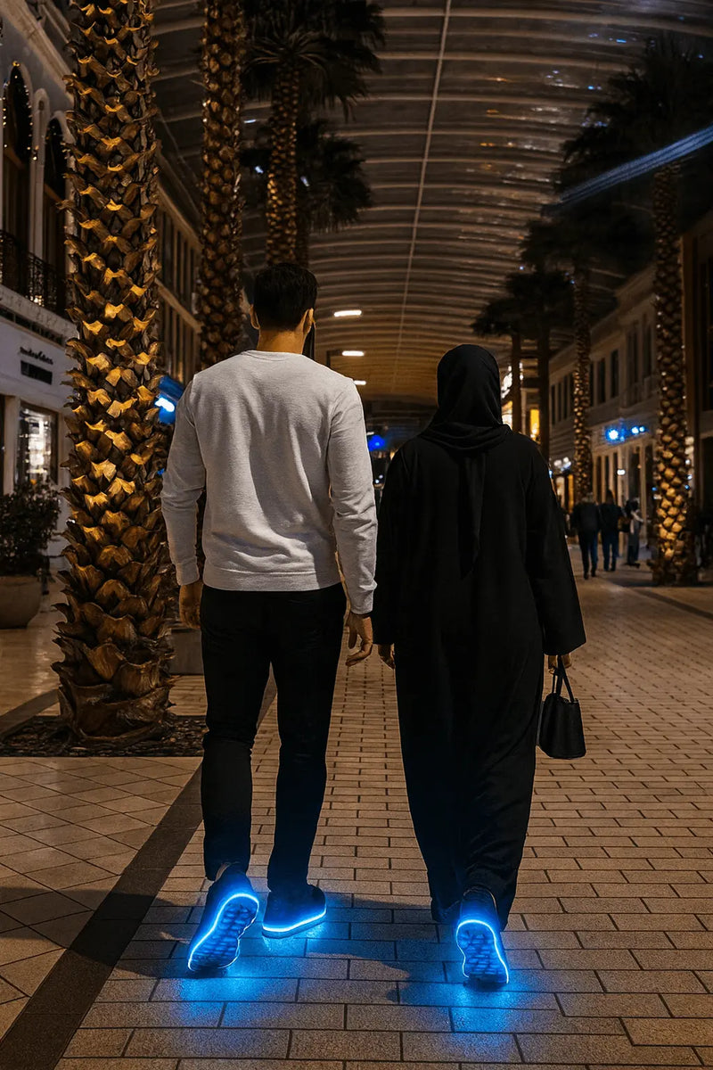 Two people walking on a sidewalk at night with glowing shoes.